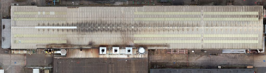 Showing an aerial view of a factory roof captured by drone.